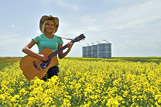 Teenager playing guitar in canola field